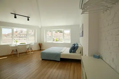 a bedroom with a bed and a desk and two windows at The Corner Studio in Varna City