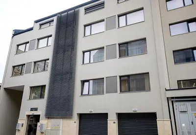 a tall white building with black shuttered windows at Casa Novara Apartments - Relax & Enjoy in Central Varna by Flat Mаnаger in Varna City