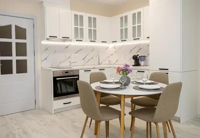 a white kitchen with a table and chairs at Casa Novara Apartments - Relax & Enjoy in Central Varna by Flat Mаnаger in Varna City