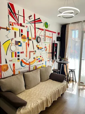 a living room with a couch in front of a colorful wall at Студия Авангард in Sunny Beach