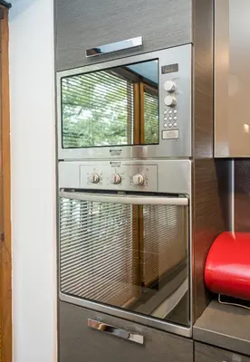 a microwave oven in a kitchen with a red stool at Cozy Flat with Two Bedrooms in Central Varna by Flat Mаnаger in Varna City