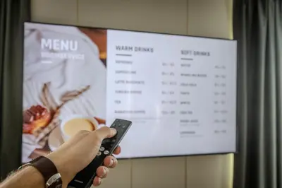 a person holding a remote control in front of a menu at Aslan Gold Hotel in Varna City
