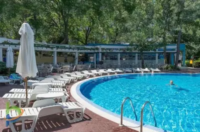 a pool with chairs and a person swimming in it at Excelsior Apartment in Sunny Beach