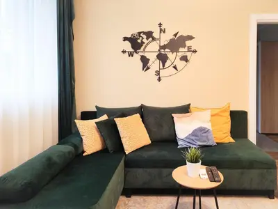 a living room with a green couch with a world map on the wall at PasTelo - 6 min to the Beach & Promenade in Varna City