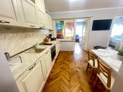 a kitchen with white cabinets and a sink and a table at 'Golden Bird' Apartment, 2 Bedrooms, Super Central in Burgas City
