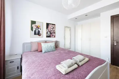 a bedroom with a pink bed with two towels on it at Chic Downtown Flat in Varna City