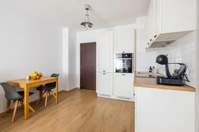 a kitchen with white cabinets and a wooden table at Chic Downtown Flat in Varna City