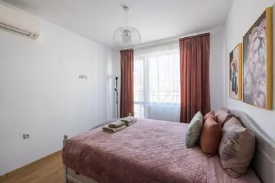 a bedroom with a bed with a pink blanket and a window at Chic Downtown Flat in Varna City