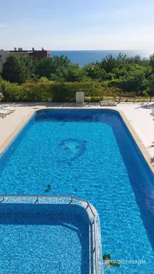 a large blue swimming pool with the ocean in the background at Апартамент Феличита in Byala