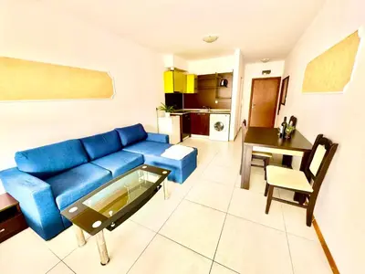 a living room with a blue couch and a table at Grand Kamelia Apartments Sunny Beach in Sunny Beach