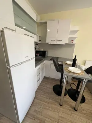 a kitchen with a white refrigerator and a table with chairs at Coastera Group Cascadas 8 in Sunny Beach