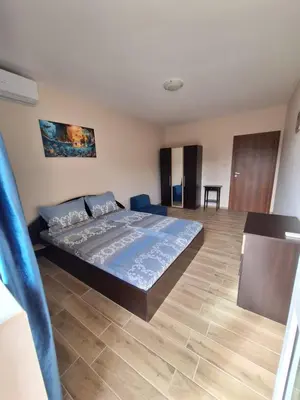a bedroom with a large bed and a wooden floor at Бобс апартаменти 2 in Kiten