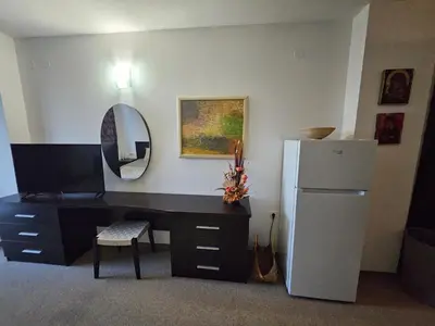 a room with a desk with a refrigerator and a mirror at Студио за двама в Сарафово in Burgas City