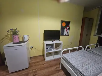 a bedroom with a bed and a desk with a television at Стая за двама в град Бургас in Burgas City