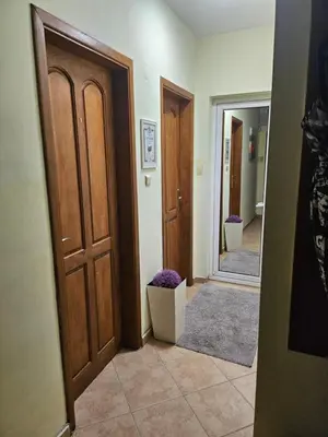 a hallway with two wooden doors and a mirror at Стая за двама в град Бургас in Burgas City