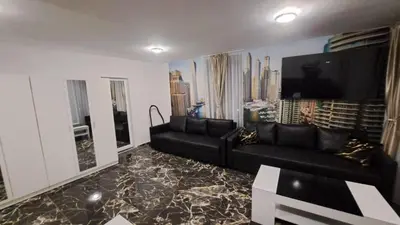 a living room with a black couch and a flat screen tv at Luxe 1 Dubai Penthouse in Obzor