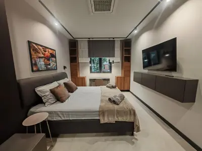 a bedroom with a large bed and a flat screen tv at Апартамент Александровска in Burgas City