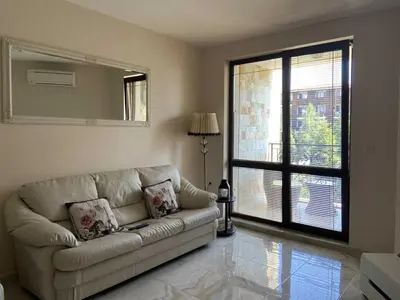 a living room with a couch and a large window at Апартамент в затворен комплекс Артур гр Свети Влас in Sveti Vlas