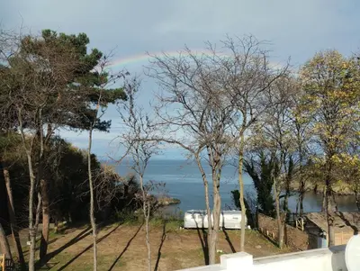 a rainbow in the sky over the water with trees at Paradise with a sea view in Burgas City