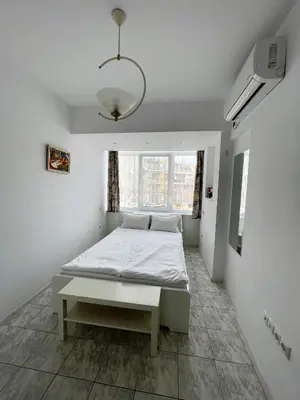 a white bedroom with a bed and a window at Velaria Centre Apartment in Burgas City