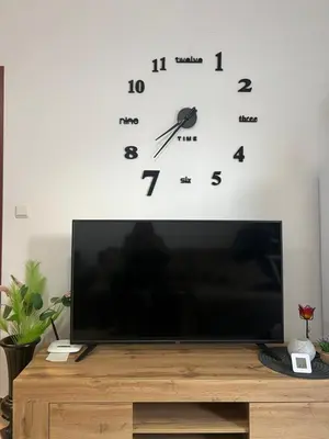 a television on a table with a clock on a wall at Siana3 in Sveti Vlas