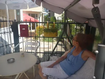 a woman sitting on a chair under an umbrella at Mechta Family Hotel in Obzor