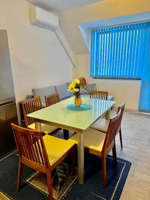 a dining room with a table with chairs and a vase of flowers at Galateya in Varna City