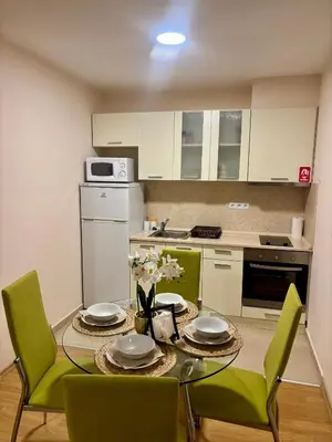 a kitchen with a table with green chairs and a kitchen with white cabinets at Luxury in Sveti Vlas