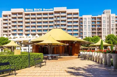 a hotel with tables and umbrellas in front of a building at Hotel Barceló Royal Beach in Sunny Beach