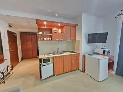 a kitchen with wooden cabinets and a white refrigerator at PALAZZO FAMILY SUITE Sunny beach in Sunny Beach