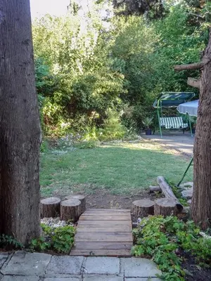 a wooden bridge with a bench next to two trees at Family нouse -Нotel Asai in Ravda