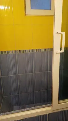 a bathroom with a shower with a yellow wall at Апартамент опера in Varna City