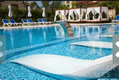 a large swimming pool with blue chairs in a hotel at Villa Valencja Apartments Family in Sunny Beach