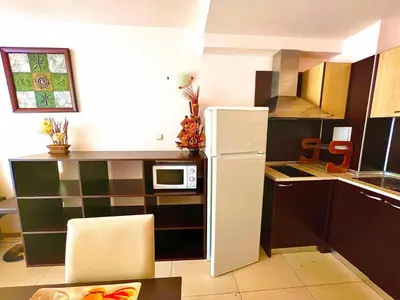 a small kitchen with a refrigerator and a microwave at Grand Kamelia Holiday Apartments Sunny Beach in Sunny Beach