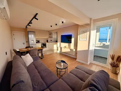 a living room with a large couch and a kitchen at Seaside Home in Burgas City
