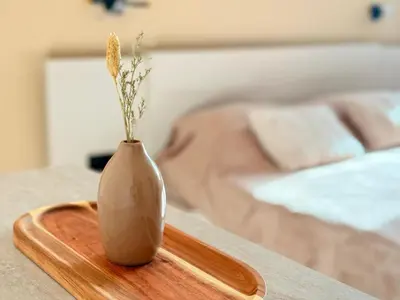 a vase on a wooden tray on a table next to a bed at Seaside Home in Burgas City