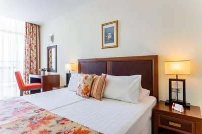 a hotel room with a large bed with pillows at Двуспален апартамент Сънсет ризорт с фронтален изглед към море in Pomorie