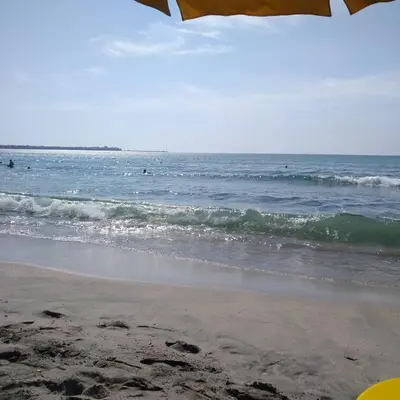 a beach with an umbrella and the ocean at Двуспален апартамент Сънсет ризорт с фронтален изглед към море in Pomorie
