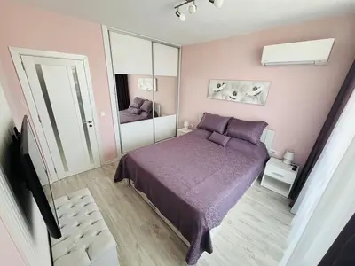 a bedroom with a purple bed and a mirror at Apartment for guests Panorama - first line sea in Burgas City