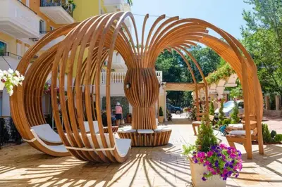 a wooden arch with chairs and flowers in a courtyard at Луксозно Студио Сладък Дом в Слънчев бряг in Sunny Beach