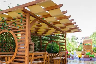 a pergola with wooden tables and chairs under it at Луксозно Студио Сладък Дом в Слънчев бряг in Sunny Beach