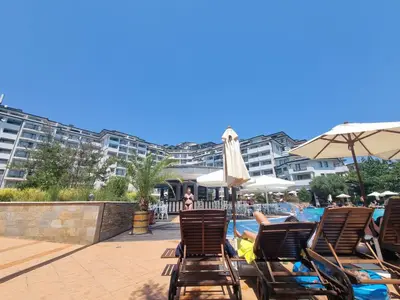 a group of chairs and umbrellas next to a swimming pool at Emerald Beach Resort & Spa, Apartment S105 in Ravda