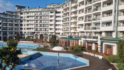 a large building with a swimming pool in front of it at Emerald Beach Resort & Spa, Apartment S105 in Ravda