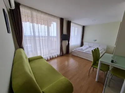 a living room with a green couch and a bed at Studio in a Resort with 9 pools in Sunny Beach