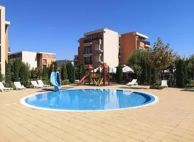a pool in a courtyard with chairs and a playground at Studio in a Resort with 9 pools in Sunny Beach