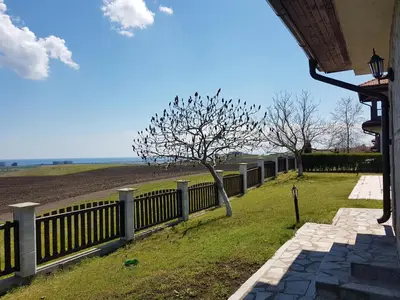 a fence with a tree next to a field at Villa Jasmin in Aheloy