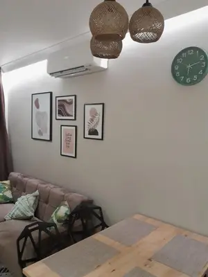 a living room with a couch and a table and a clock at Garden of Eden- MintGarden- Sveti Vlas in Sveti Vlas