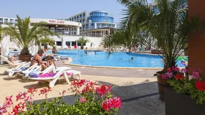 a group of people sitting on lounge chairs in a swimming pool at KJ Apartments - SwimmingPool - 3 Min From the Beach in Burgas City