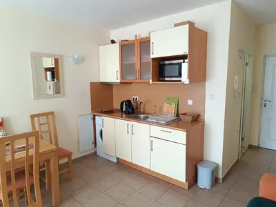 a small kitchen with white cabinets and a table at Aquamarin Studio B - Słoneczny Brzeg-Nesebyr in Sunny Beach