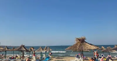 a beach with many chairs and umbrellas and the ocean at Galqna in Sozopol